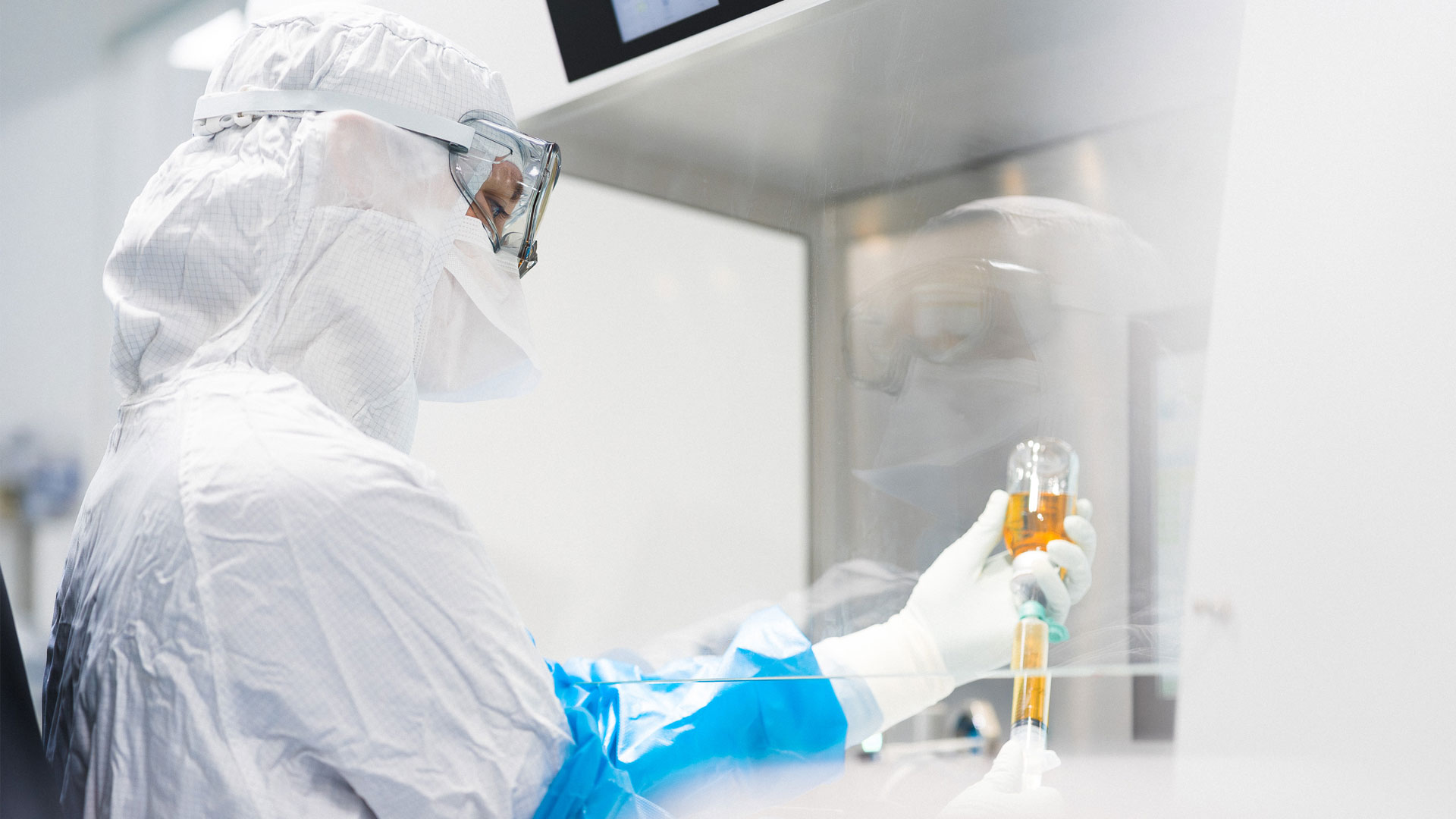 Fachkraft zieht im Reinraum an der Werkbank eine Infusionslösung auf – aseptische Herstellung patientenindividueller Therapien.